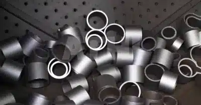 Máquina de jateamento Tumblast limpando um lote de pequenas peças fundidas de ferro.